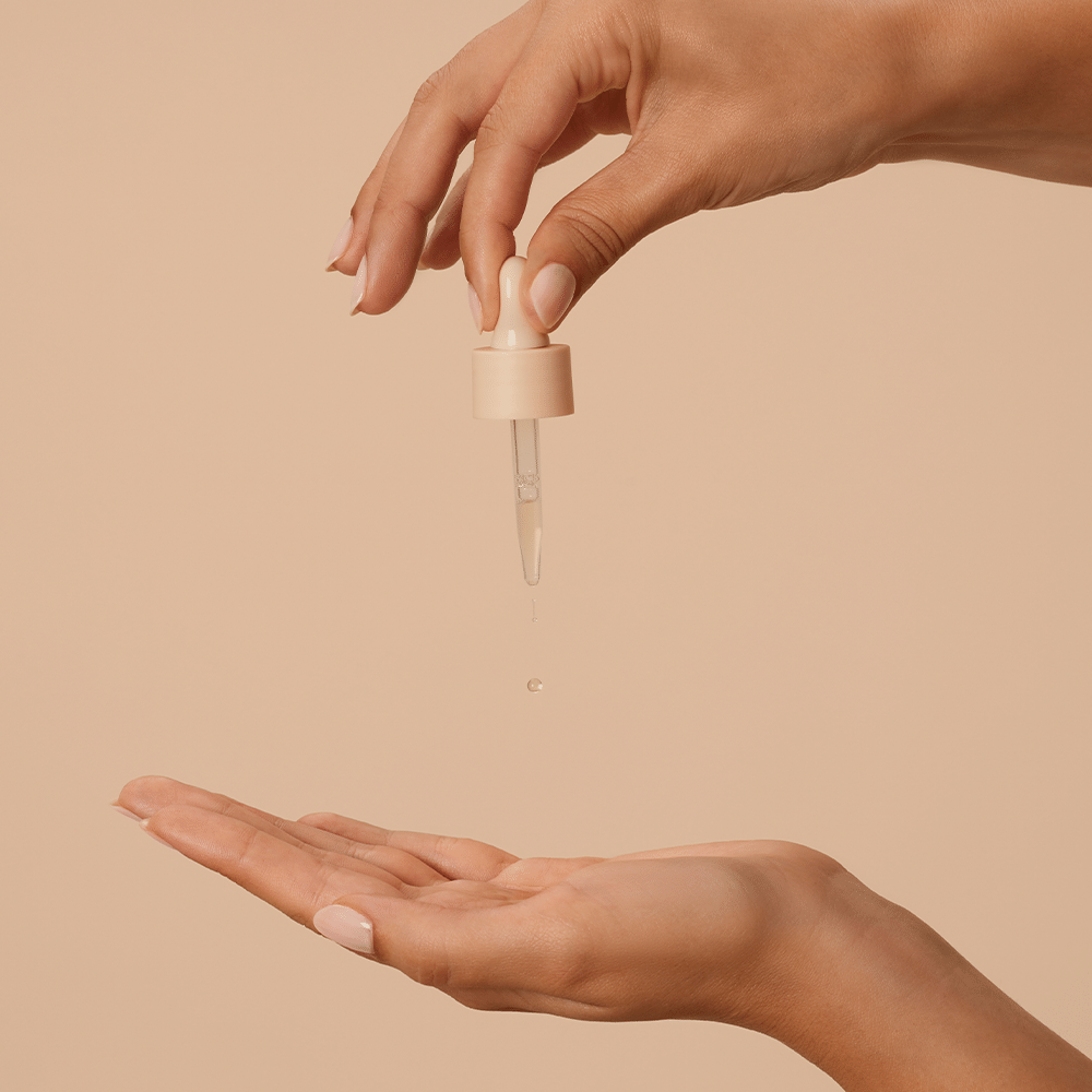 Woman using dropper to drop the Divine Ritual™ Boost of Balance concentrate into the palm of her hand