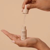 Woman holding the Divine Ritual™ Boost of Rejuvenation bottle in the palm of her hand with the dropper above