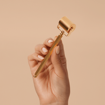 Woman holding the gold Divine Ritual™ Derma Roller