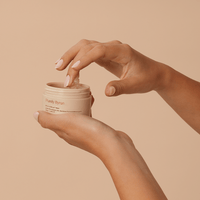 Woman scooping the Divine Ritual™ Balm from the pot with her fingertips